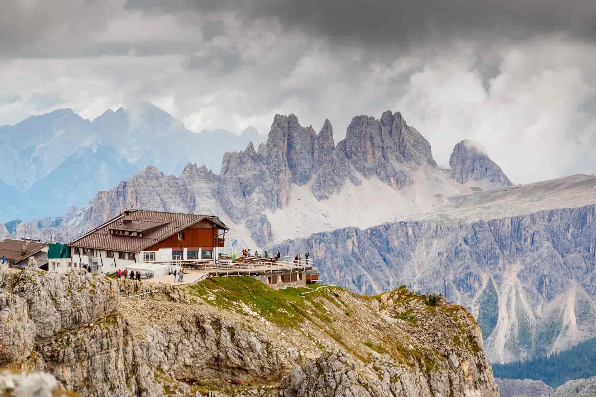 Rifugio Lagazuoi mountain hut on rocky ridge with dramatic Dolomites peaks under cloudy sky.