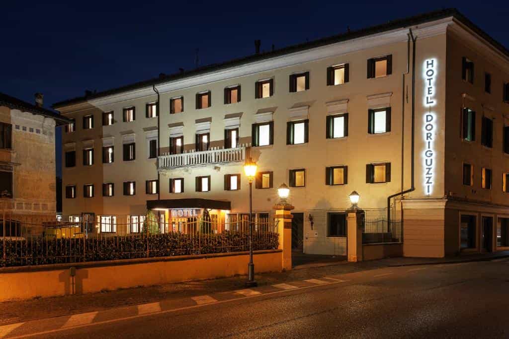 Hotel Doriguzzi illuminated at night next to a street with street lamps