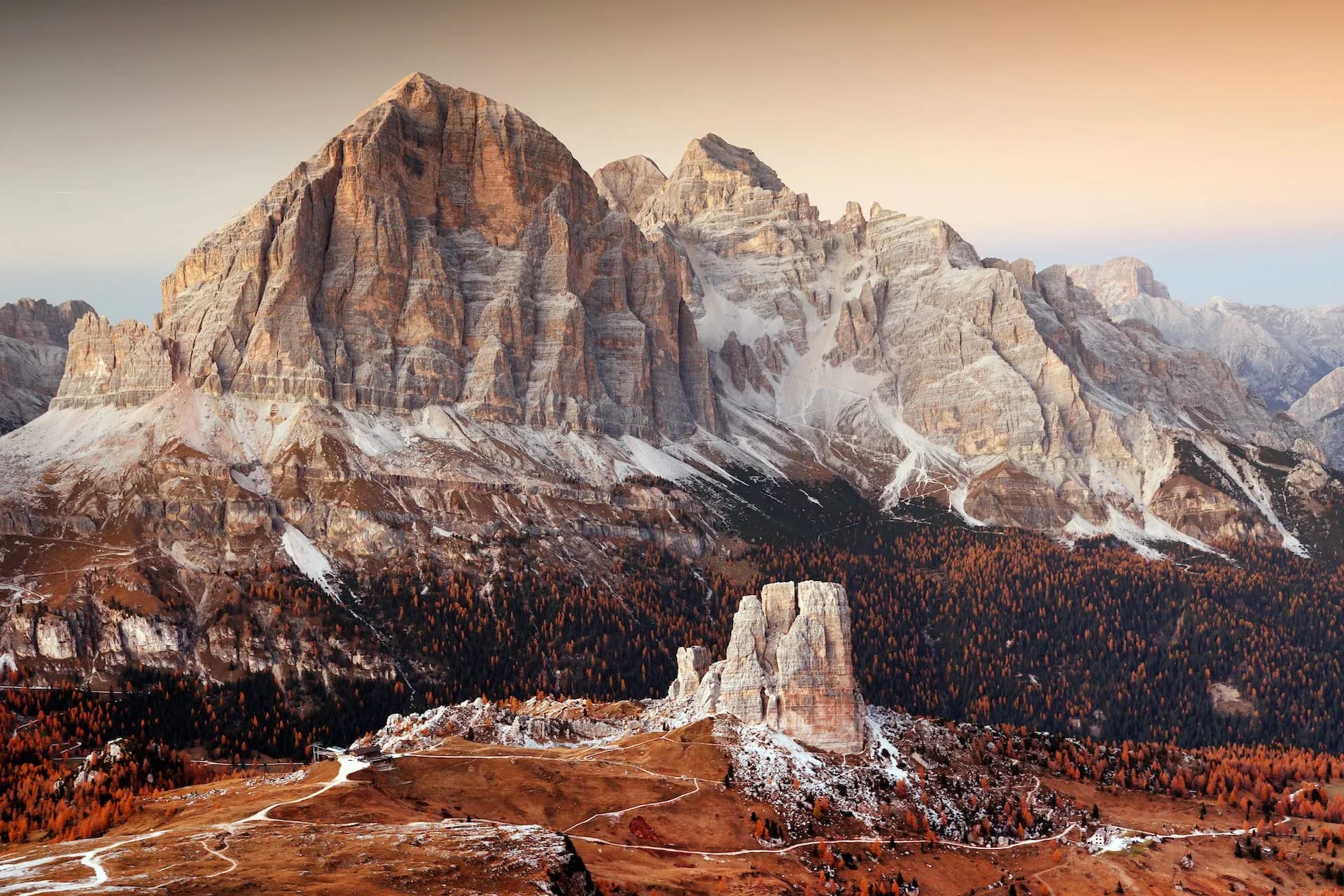 Cinque Torri and Tofana mountains with autumn foliage and early snow at sunset.