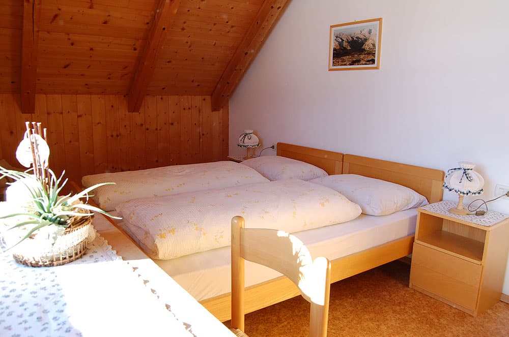 Bedroom in alpine refuge with wood paneling, double bed, and mountain art.