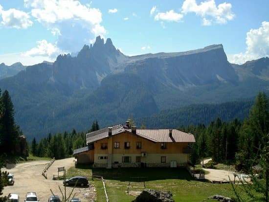 Rifugio Angelo Dibona mountain hut with parking below jagged peaks and dense forest.