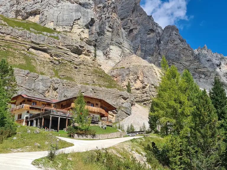 Rifugio Angelo Dibona mountain hut nestled against massive rocky slopes under a blue sky.