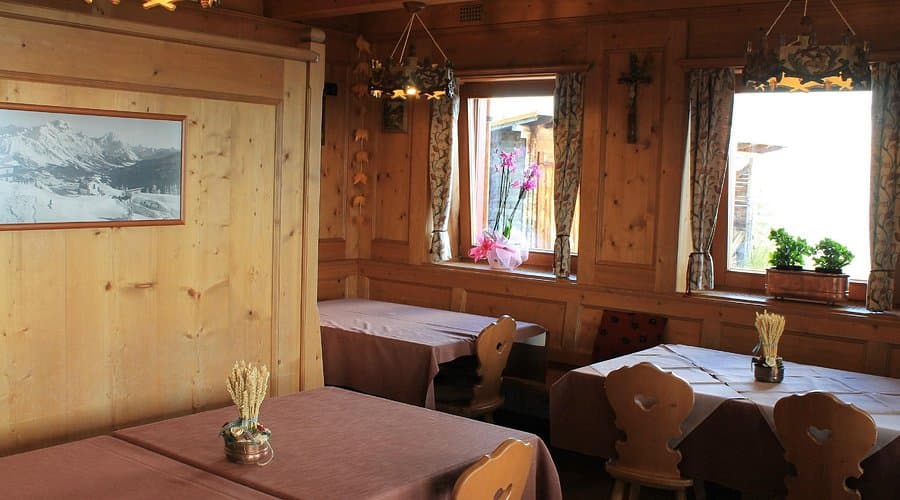 Rustic dining room with wood paneling, set tables, and mountain photo at Rifugio Duca D'Aosta.
