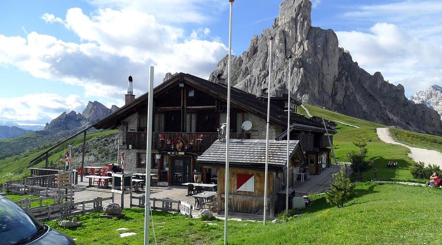 Berghotel Passo Giau mountain lodge with outdoor patio against dramatic rocky peaks.