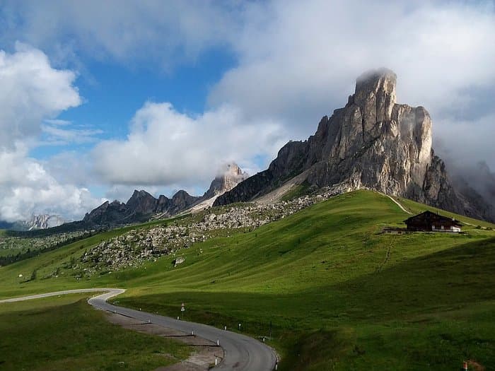 Winding road near Berghotel Passo Giau, with dramatic rocky peak shrouded in clouds.