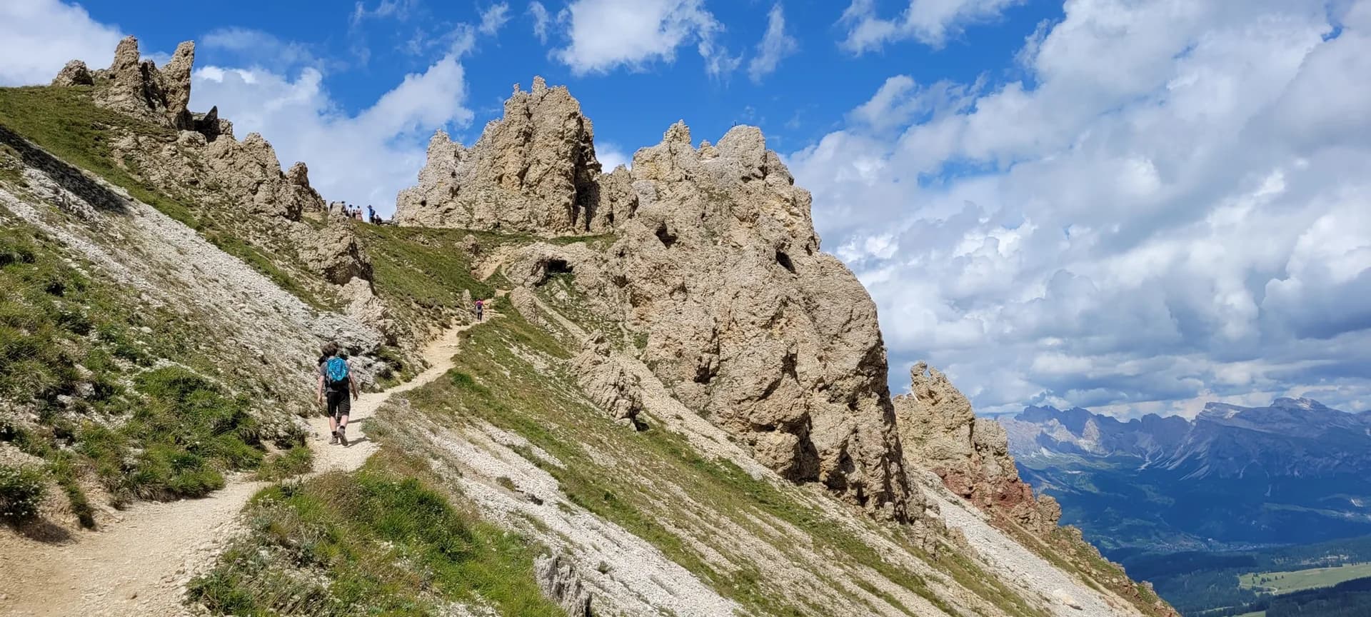 Hikers on a trail through the jagged rock formations of Seiser Alm in the Dolomites.