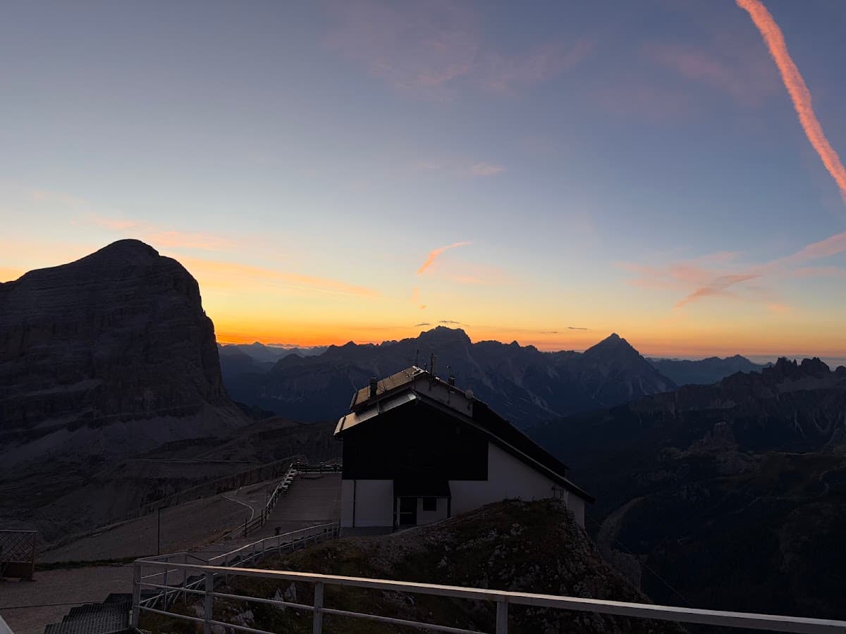 Alpine mountain refuge during sunset with jagged peaks in the background