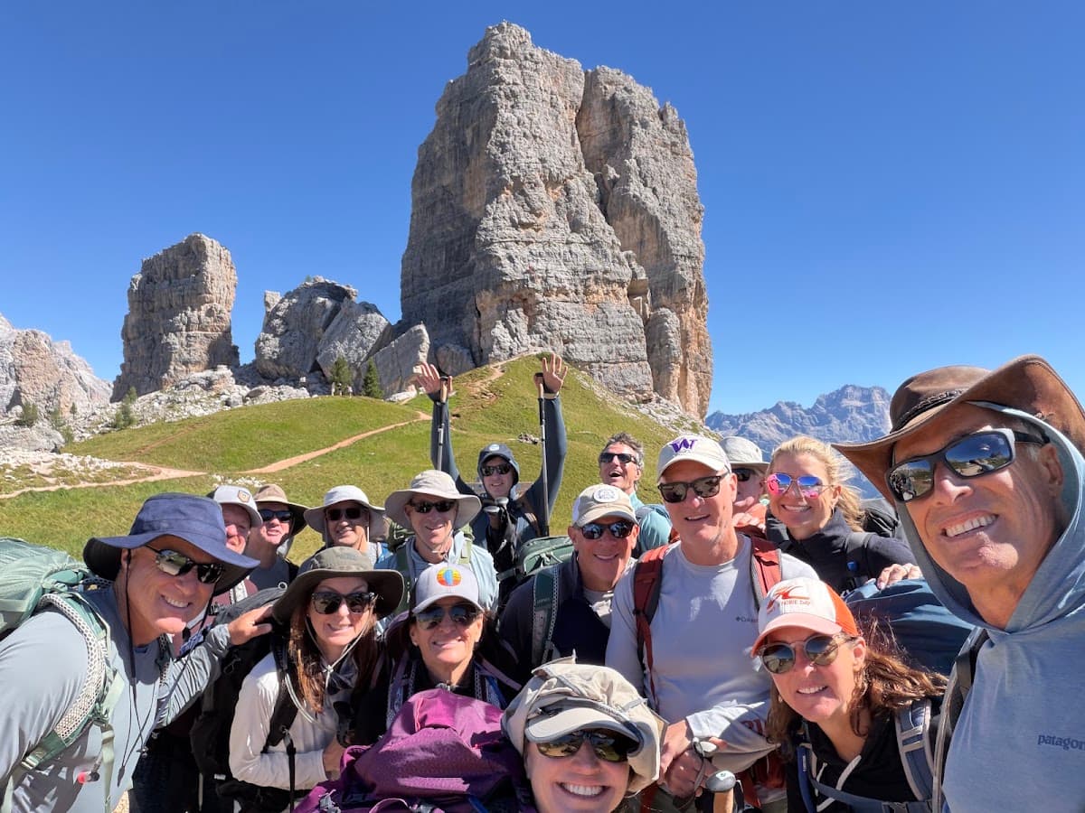 Group of hikers posing for selfie in front of rocky mountain peaks