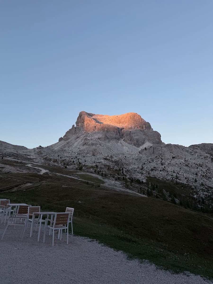 Outdoor tables and chairs overlooking a rocky mountain peak at sunset