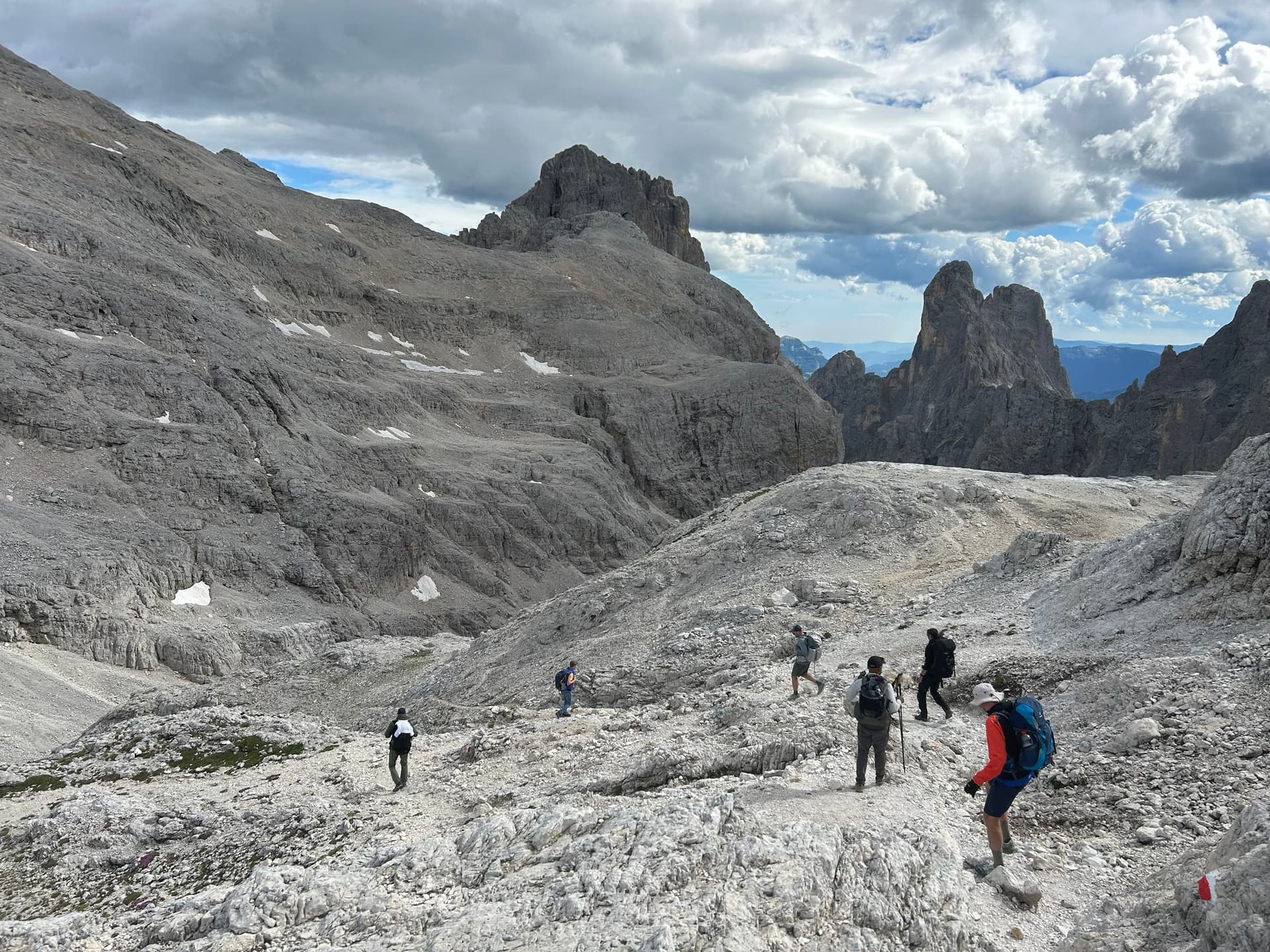 Hikers crossing a rocky mountain plateau under a cloudy sky