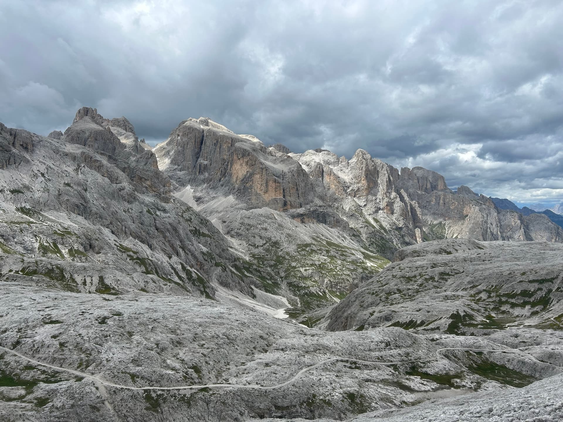 Grey plateau and rocky mountain peaks under a cloudy sky