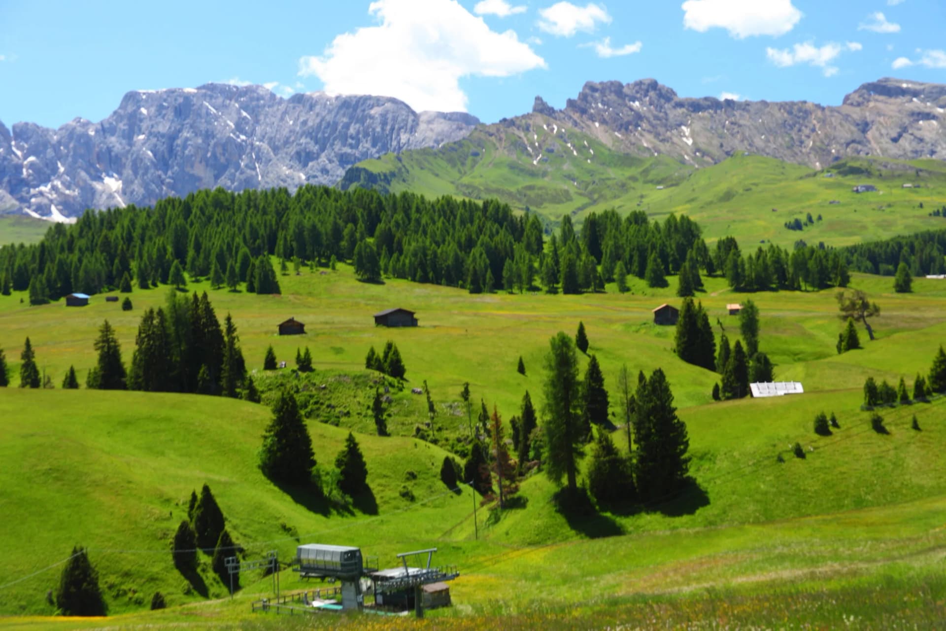 Hiking towards Roszahne Ridge on Seiser Alm with green meadows and snowy mountains.