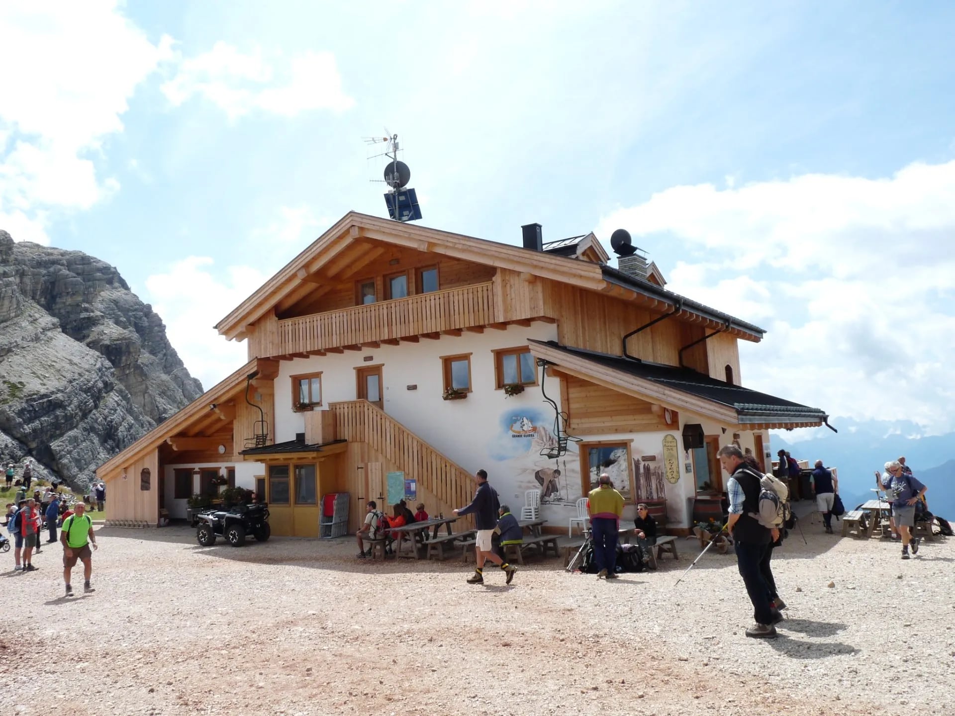Rifugio Averau mountain hut with hikers resting outside against a backdrop of rocky peaks.