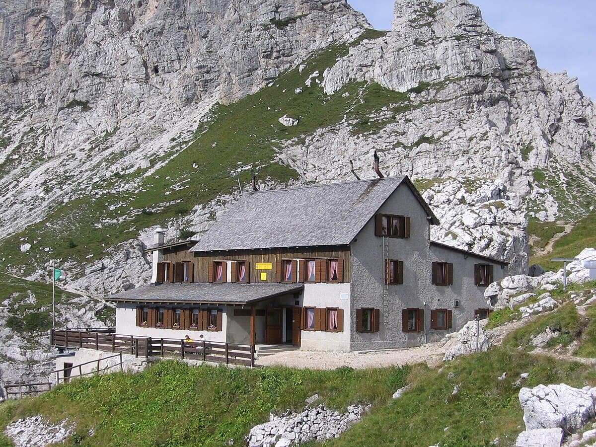 Rifugio Adolfo Sonino al Coldai mountain hut nestled against a steep, rocky alpine slope.