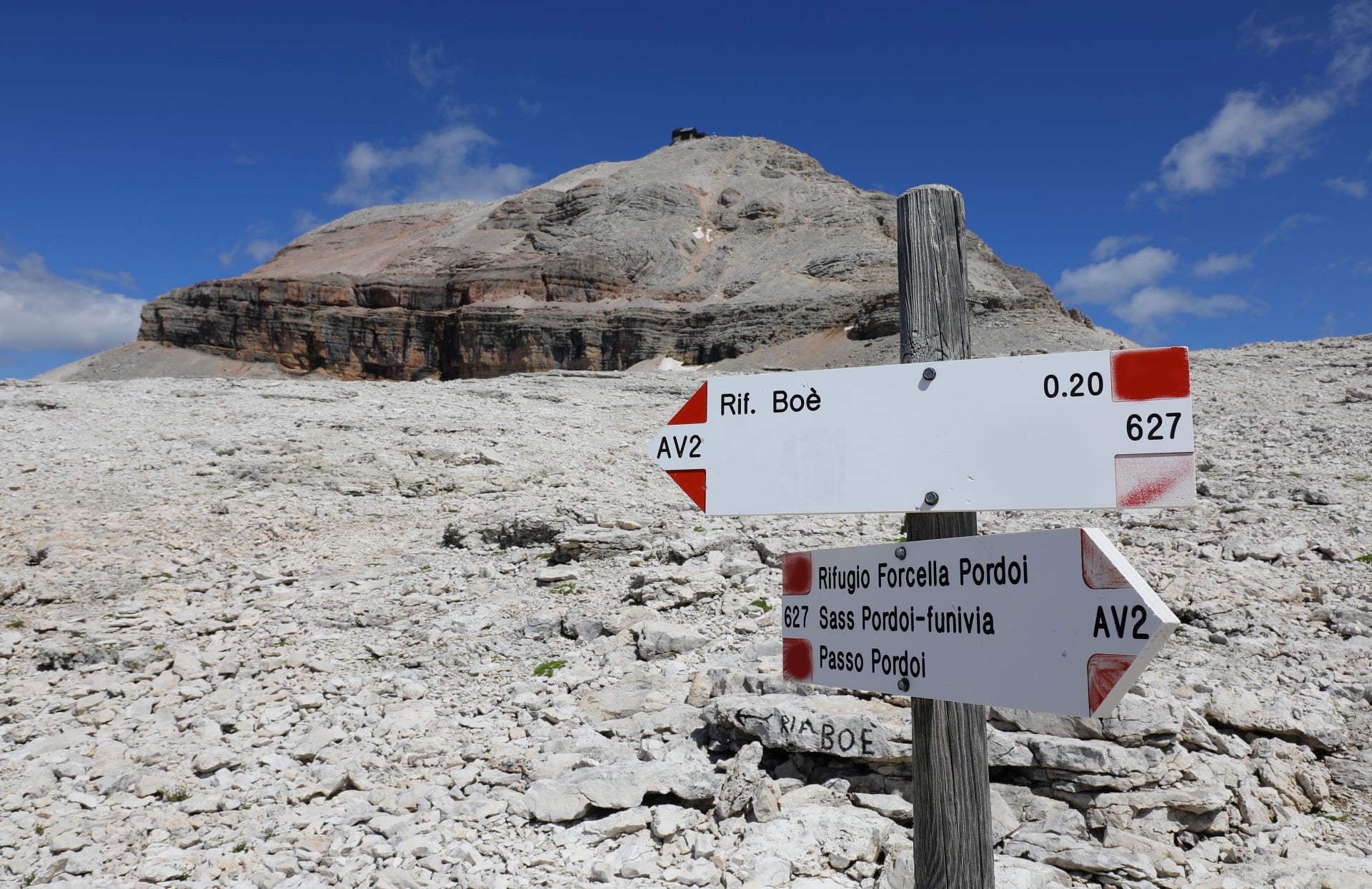 directional signs with mountain locations in Italian and walking times on the Alps