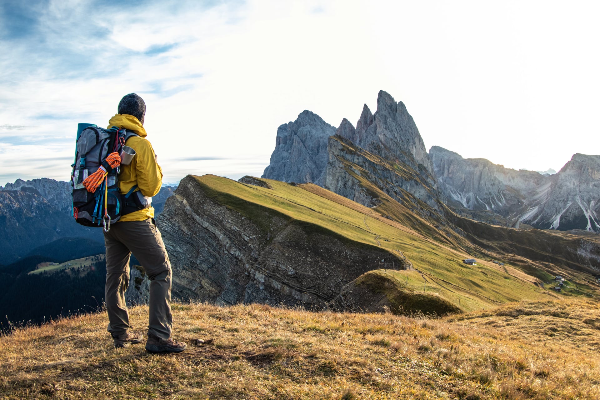 Jeune homme en randonnée au sommet de la montagne Seceda au lever du soleil. Sac à dos, veste jaune, bottes, bonnet. Voyage vers Puez Odle, Dolomites, Trentino, Italie.