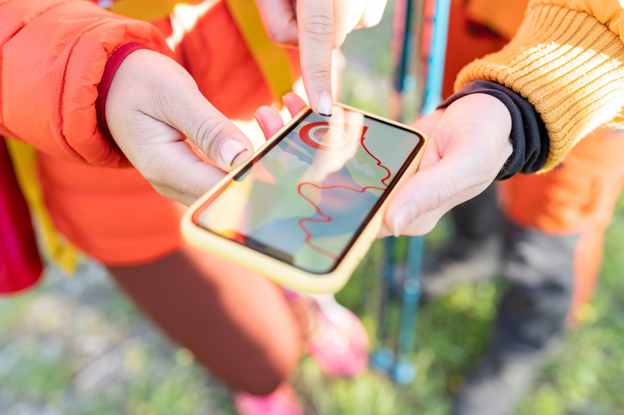 Couple of hikers looking at a map and smartphone at the edge of the forest road, snow-capped Sierra Mountain.