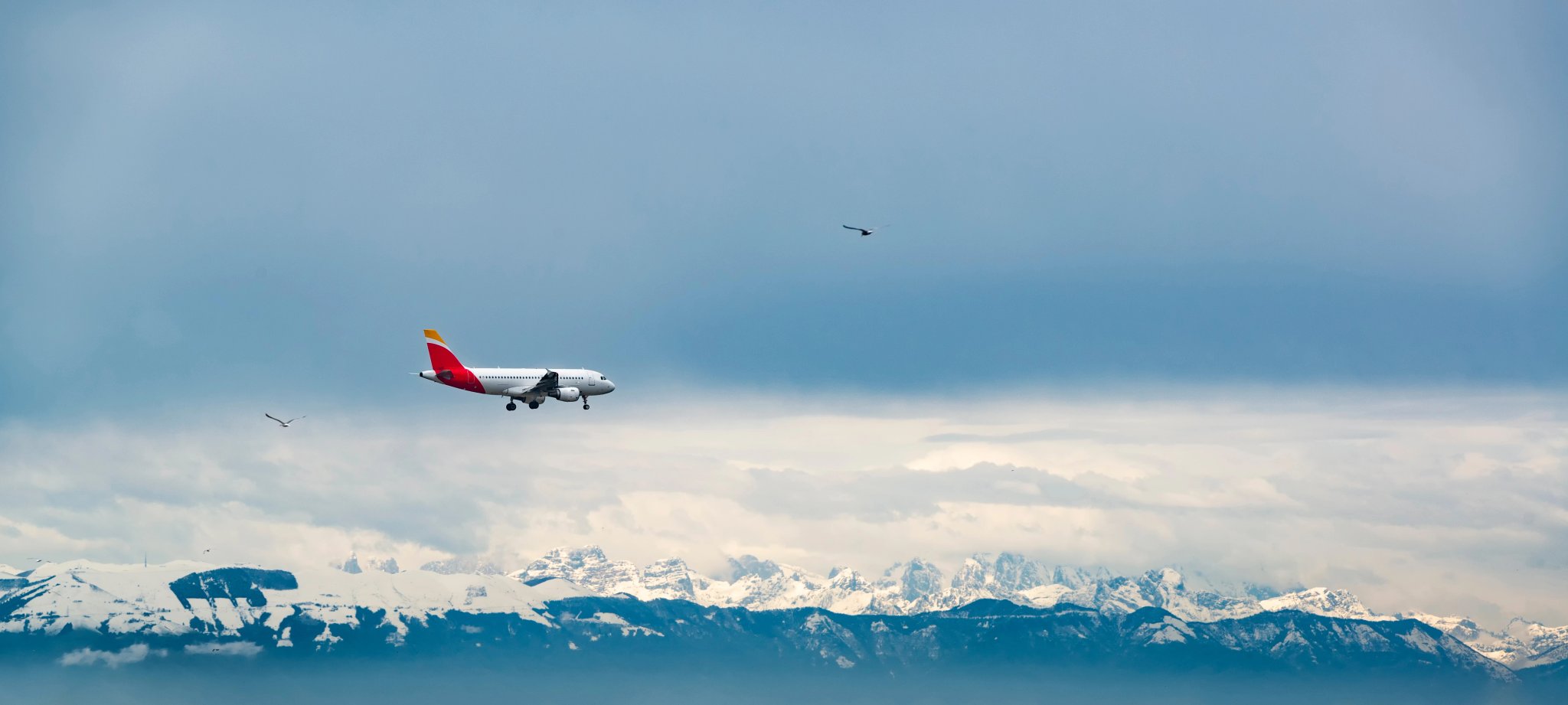 Passenger plane fly above Dolomites mountains covered by snow.