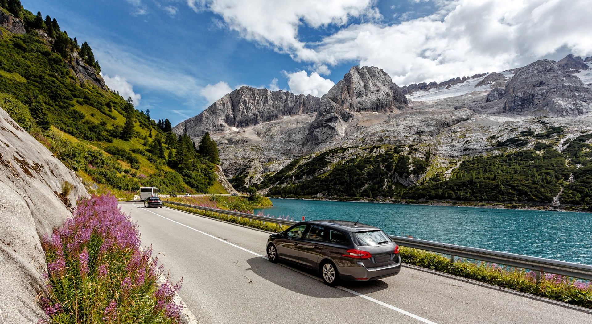 Awesome alpine highland in sunny day. Colorful spring scene. Summer view of Asphalt road near Fedaia lake and Marmolada mountain. Amazing natural scenery in Dolomites Alps. Picture of wild area