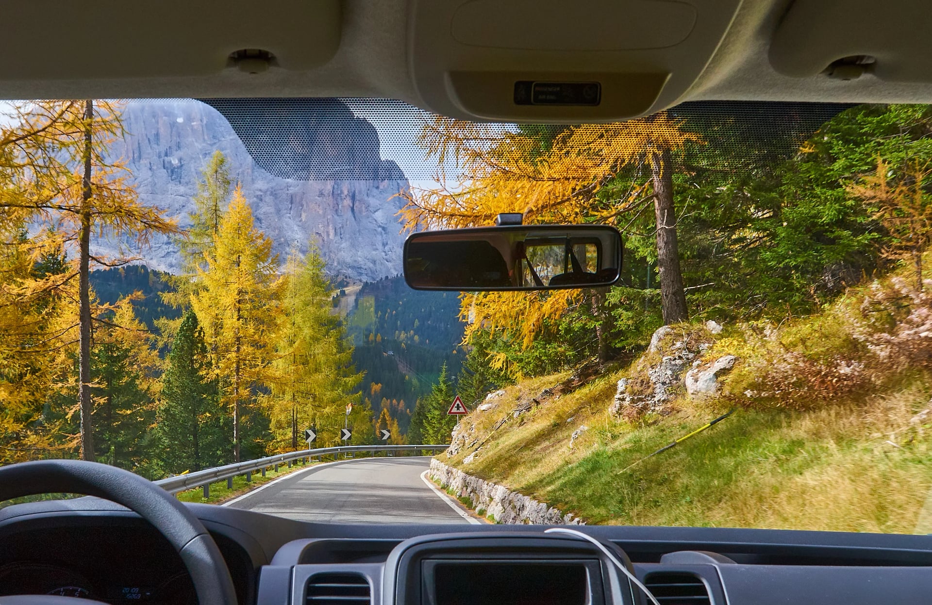 view on the Alps through the windscreen of the car while driving on the curvy road.