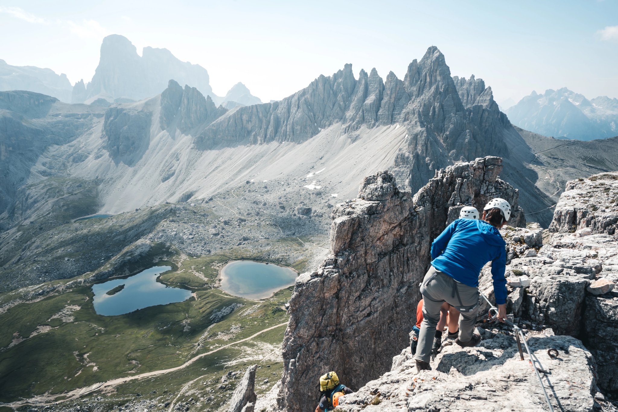 Folk med klatreudstyr er på vej ned fra Toblinger Knoten toppen, i baggrunden er tre cime di lavaredo, Italien