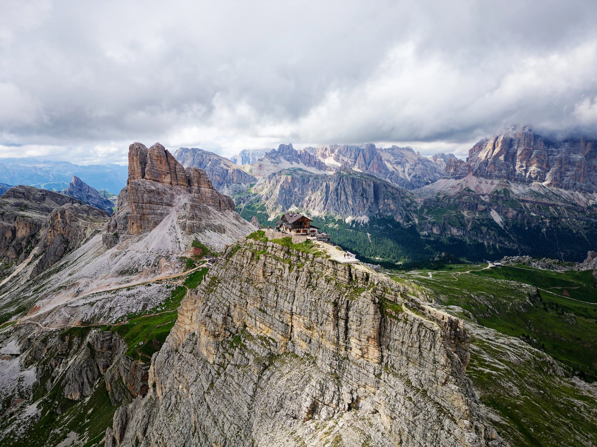 Luftbild av Rifugio Nuvolau, den äldsta bergshyttan i Dolomiterna, Italien. Moln täcker bergen i bakgrunden. Vackra destinationer för vandrare och alpinister. Cinematisk bild