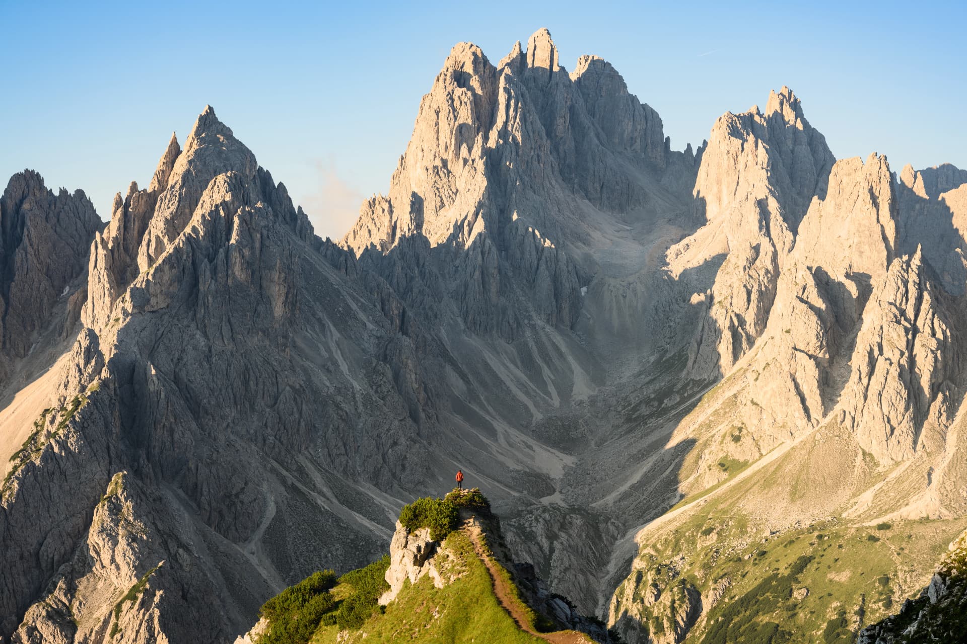 Stunning view of a tourist on the top of a hill enjoying the view of the Cadini di Misurina during sunrise. Cadini di Misurina is a group of mountains located in the Dolomites, Italy.