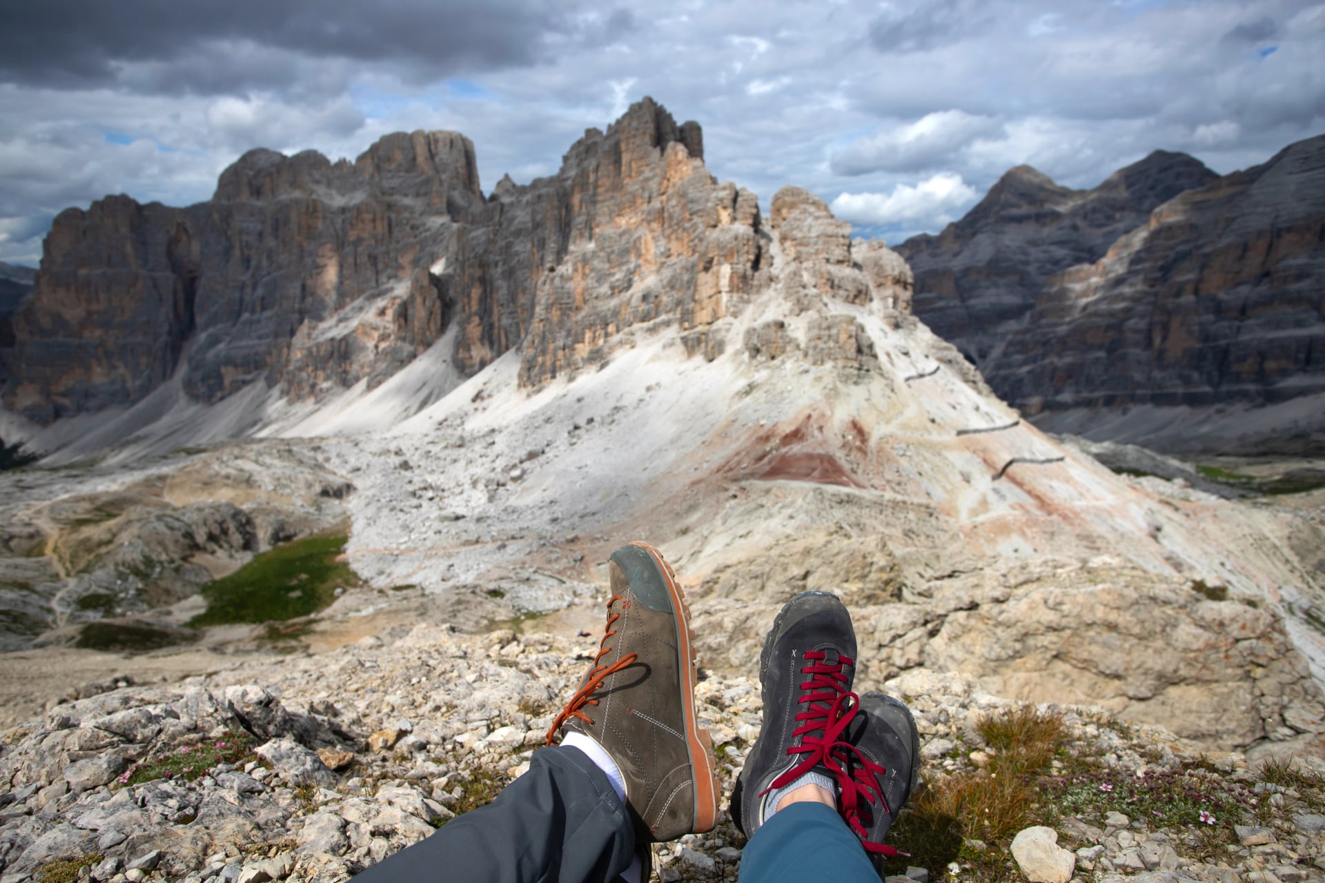 Trekking boots of a hiker couple while sitting on top of a mountain in Dolomites, Italy