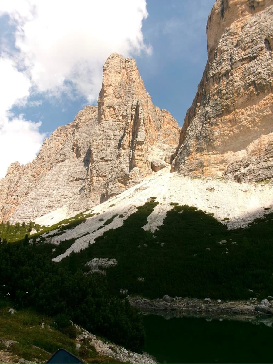 Rugged alpine mountain peaks with steep rocky cliffs and dark pine forest below