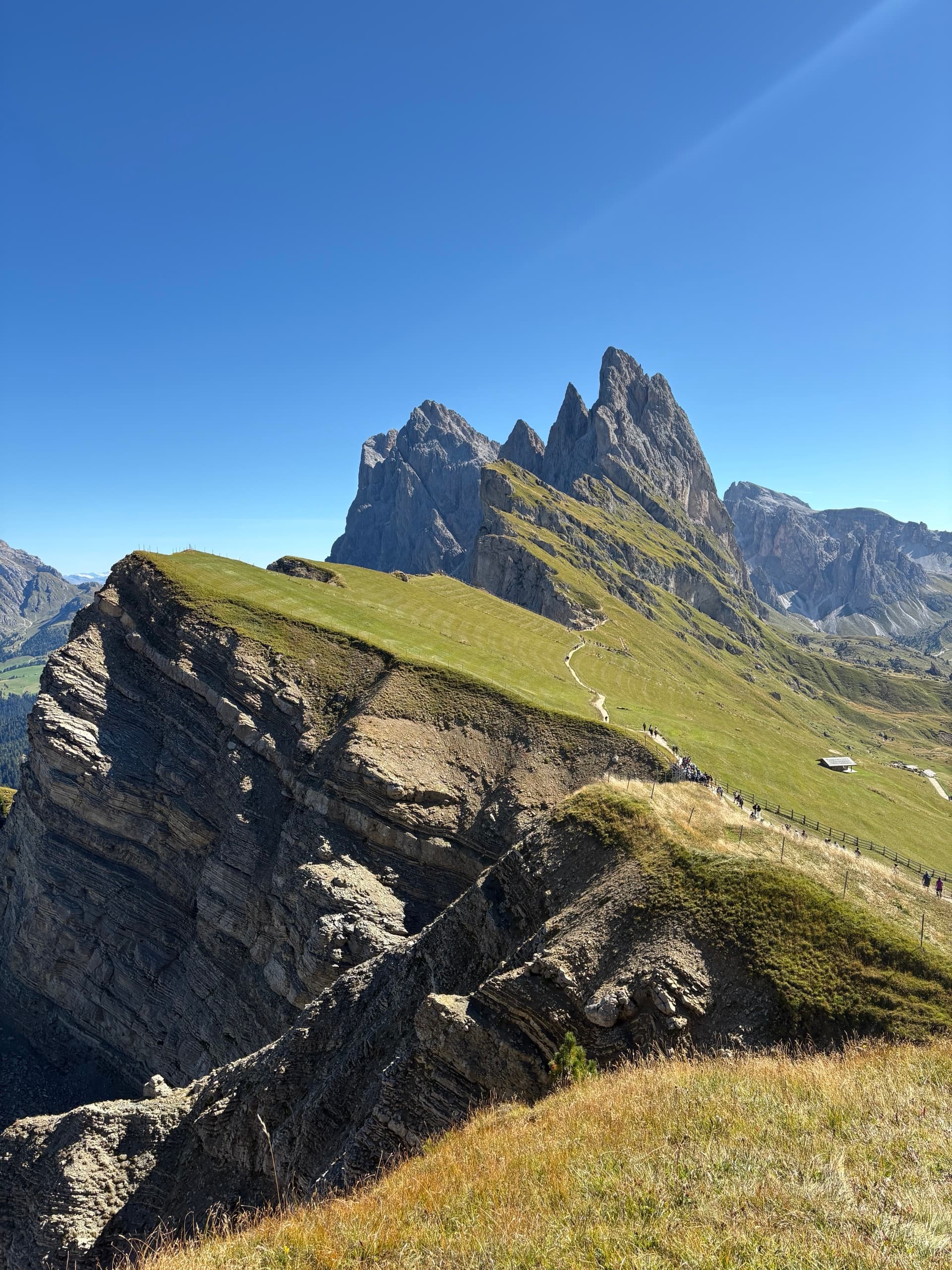 Seceda ridge with jagged mountain peaks and green grassy slopes under blue sky