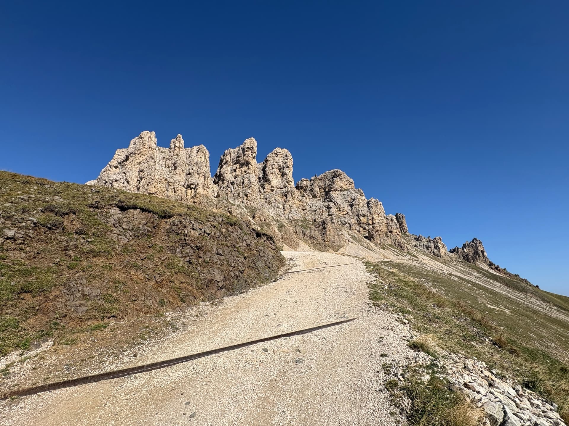 Gravel track below jagged rock pinnacles against a clear blue sky