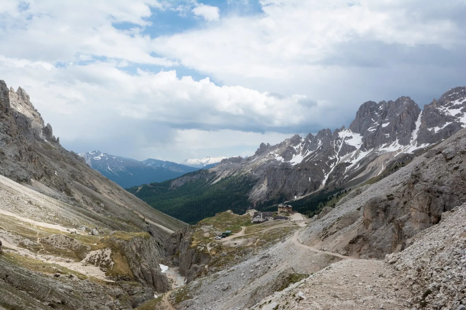 Hiking down to Rifugio Vajolet in the Dolomites with rocky slopes and snow-capped peaks