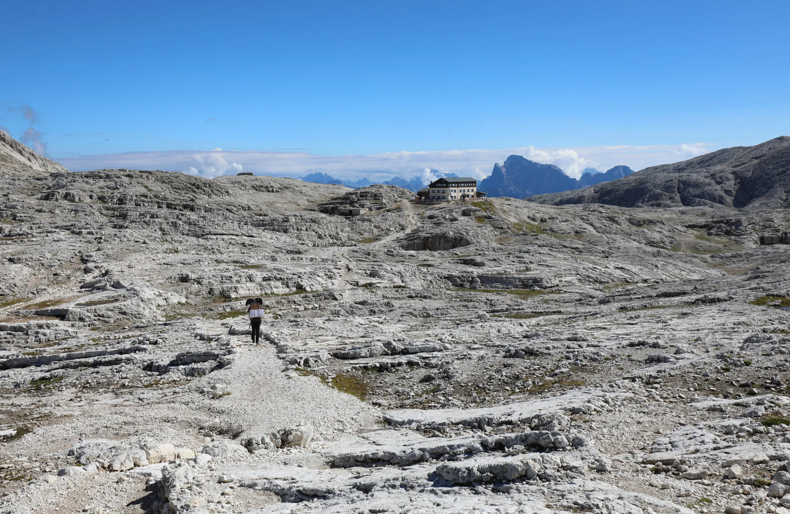 Ödsligt, nästan månlikt panorama över de europeiska alperna på sommaren och en godstransportör som går längs den steniga stigen